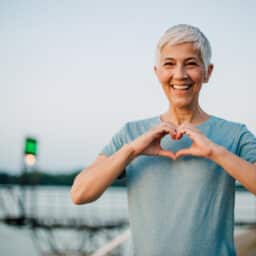 Woman forming heart in front of her chest with her hands looking happy