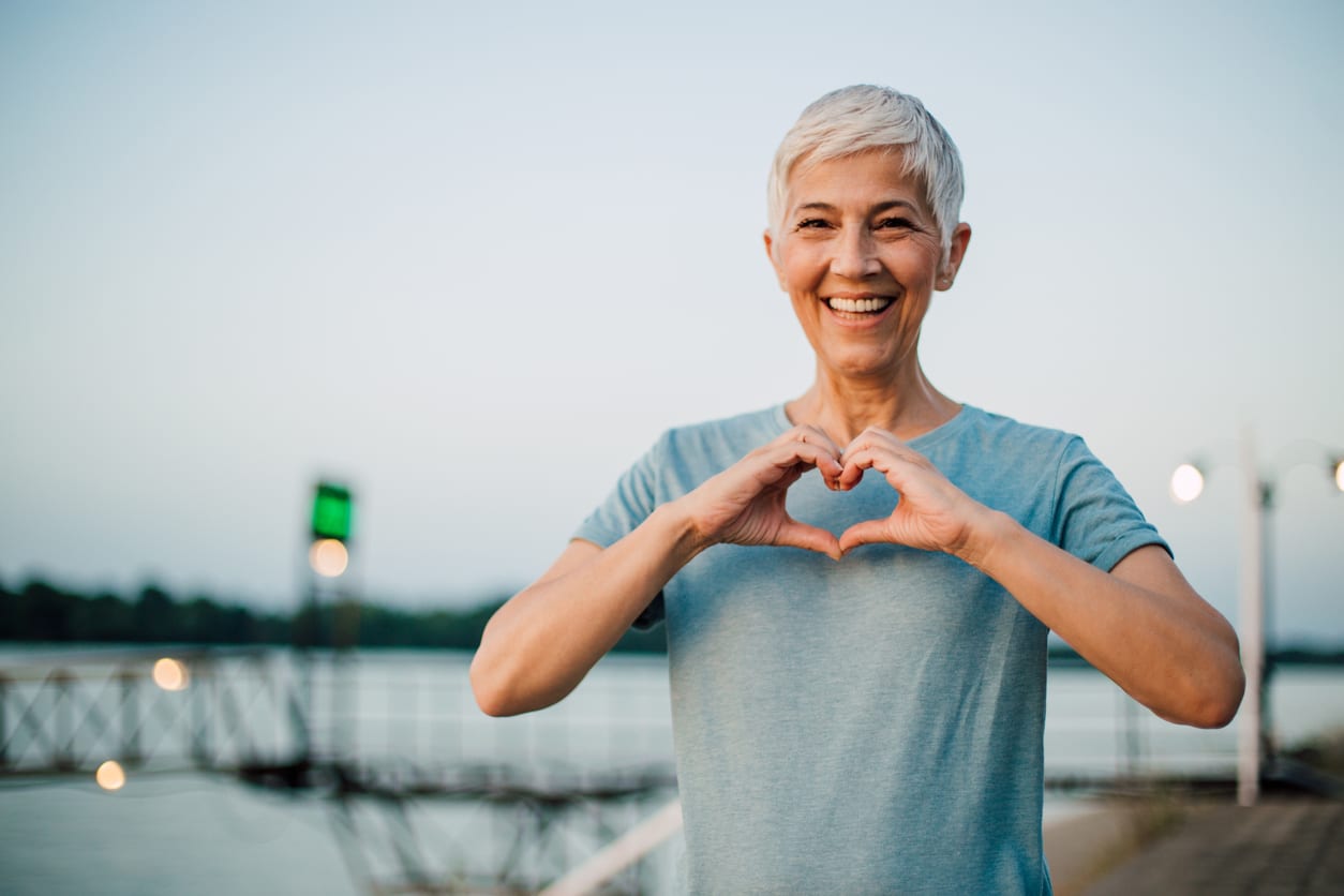 Woman forming heart in front of her chest with her hands looking happy