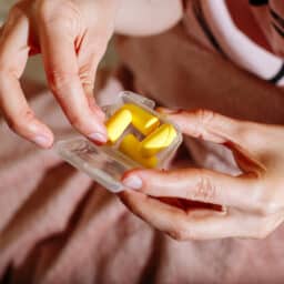 Woman holds container of yellow earplugs