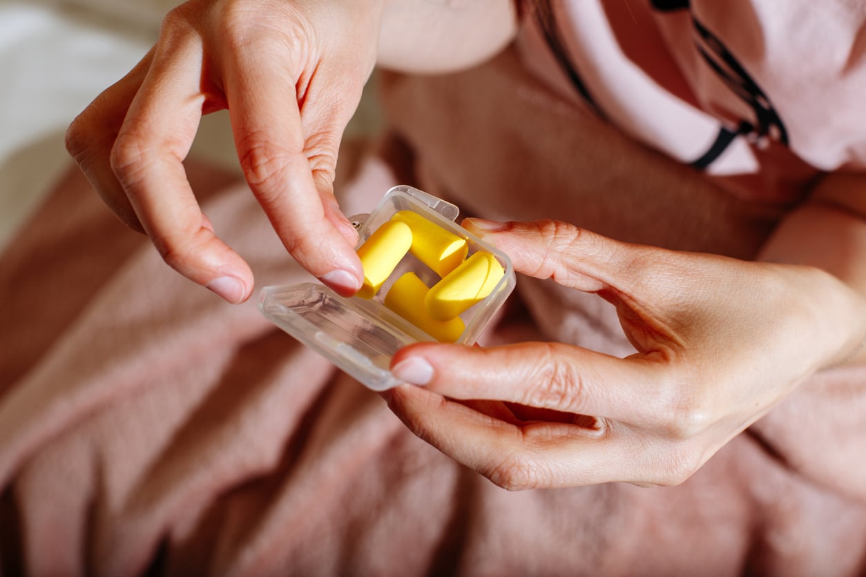 Woman holds container of yellow earplugs 